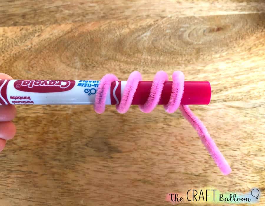 Pink pipe cleaner curled round a marker pen.