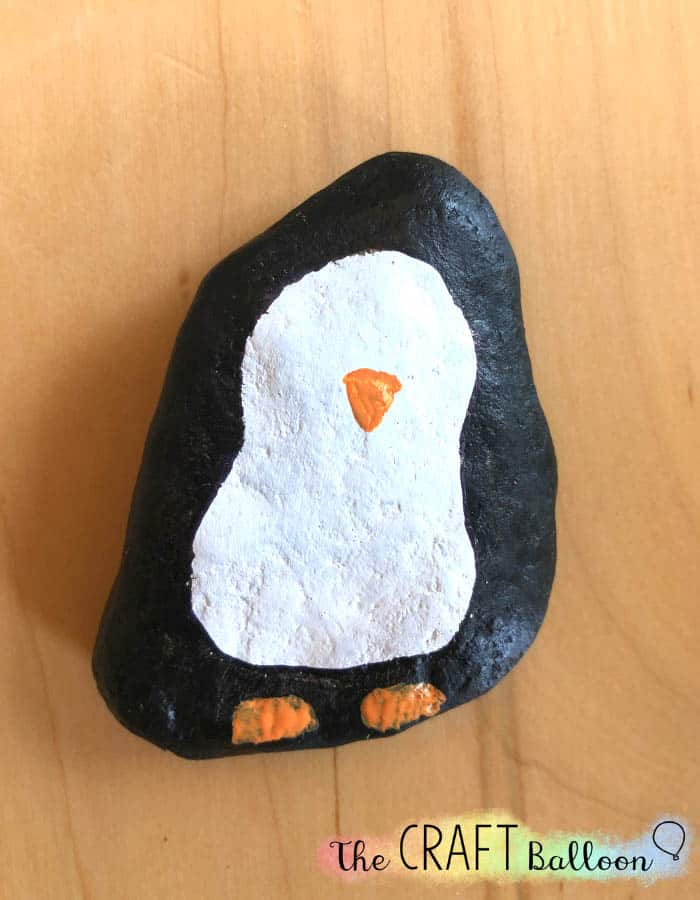penguin painted rock with beak and feet added