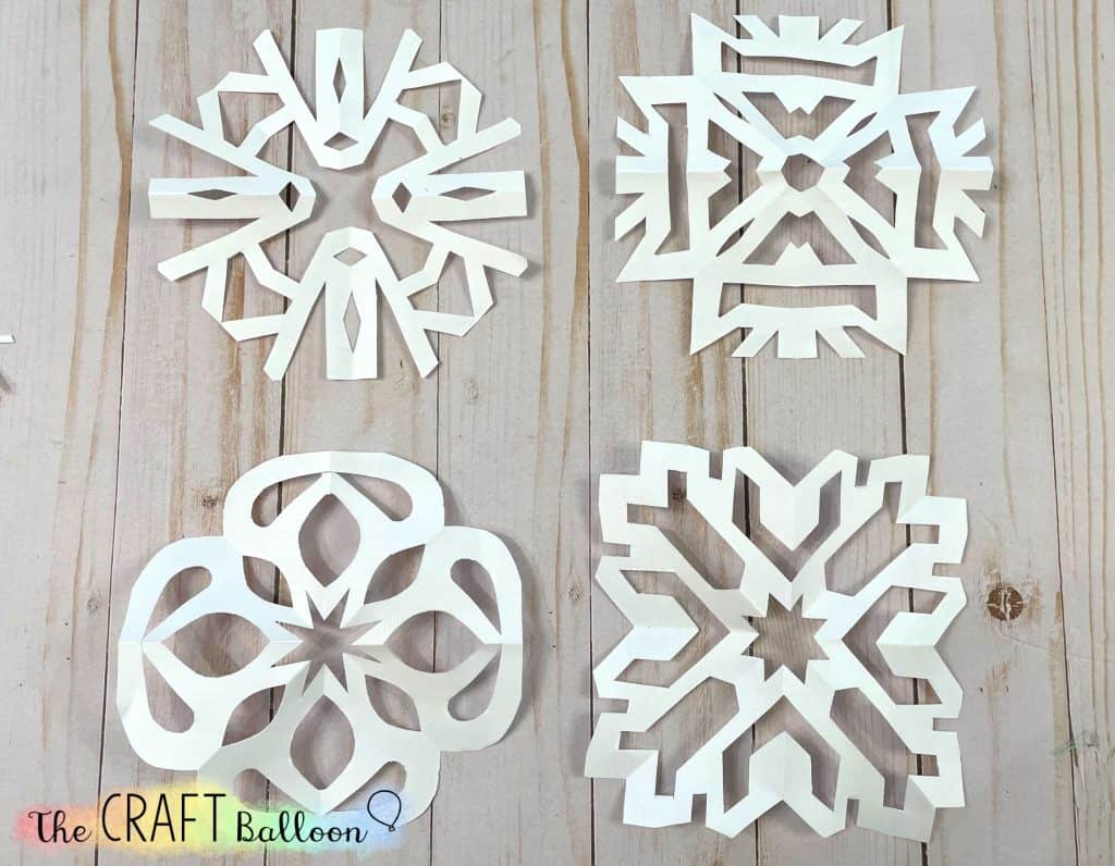 Four paper snowflakes laid out on tabletop.