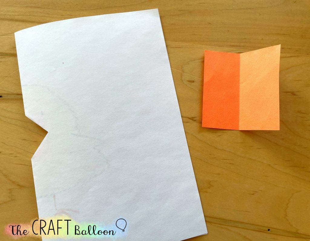 folded white paper and small folded square of orange paper