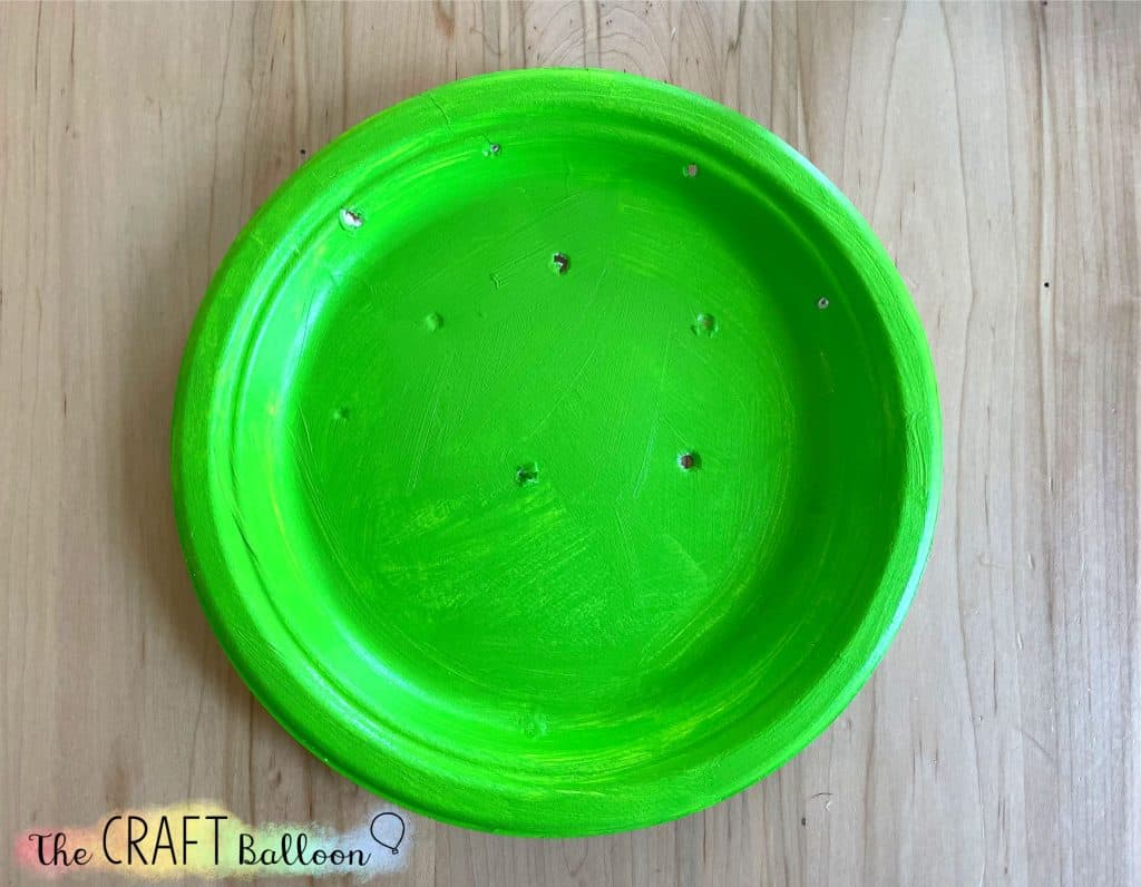 paper plate painted green with holes made